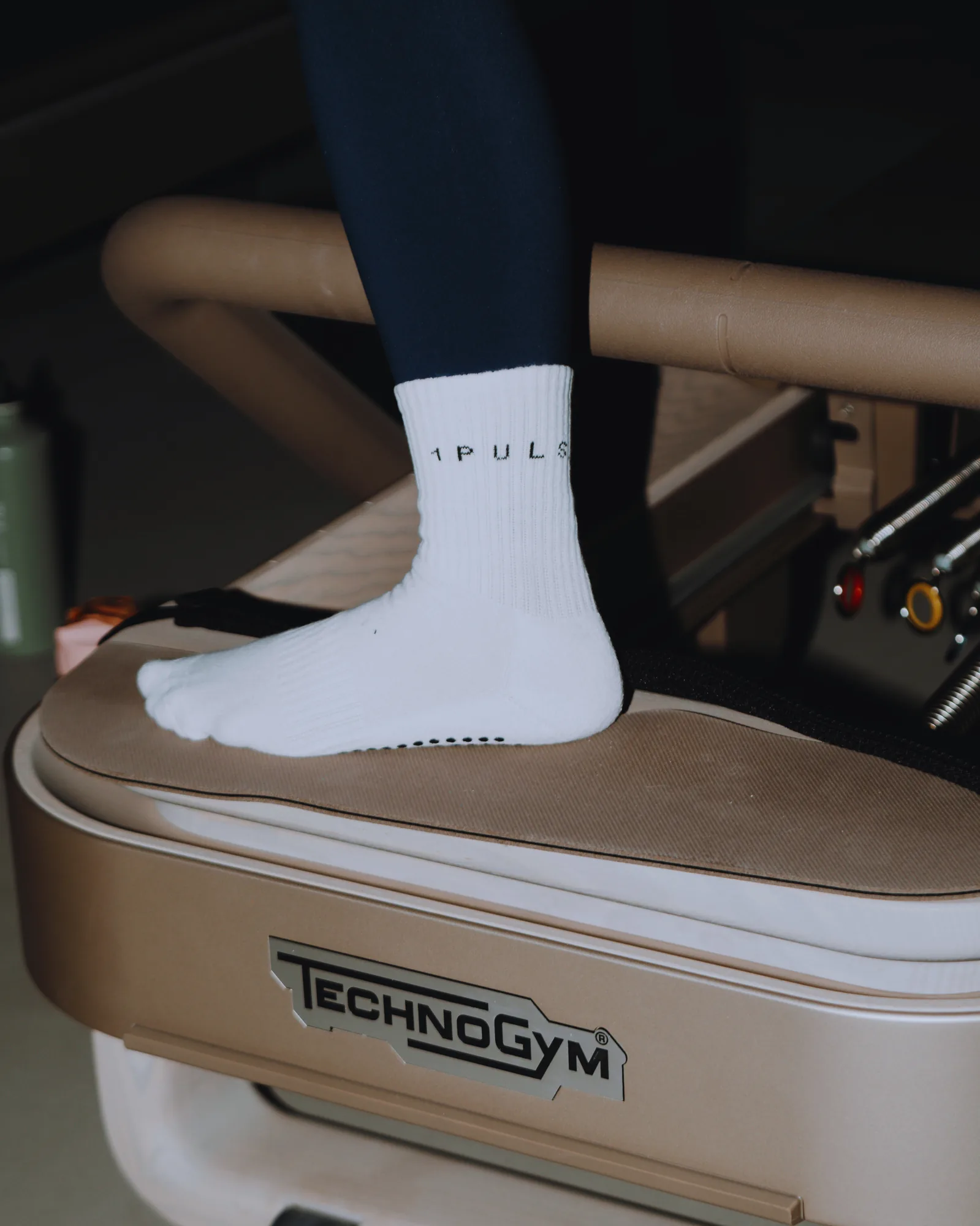 Foot in a 1PULS grip sock resting on a Technogym reformer