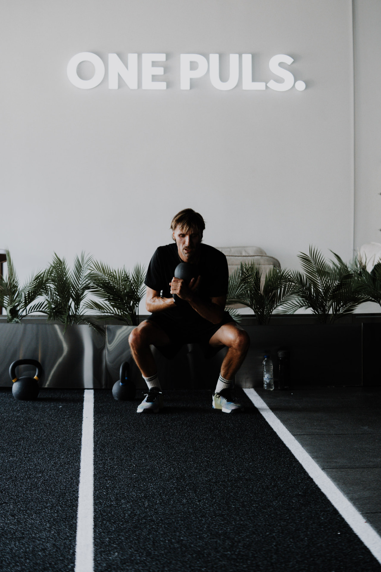 Member training alone with a kettlebell on the track under the ONE PULS sign, Brussels