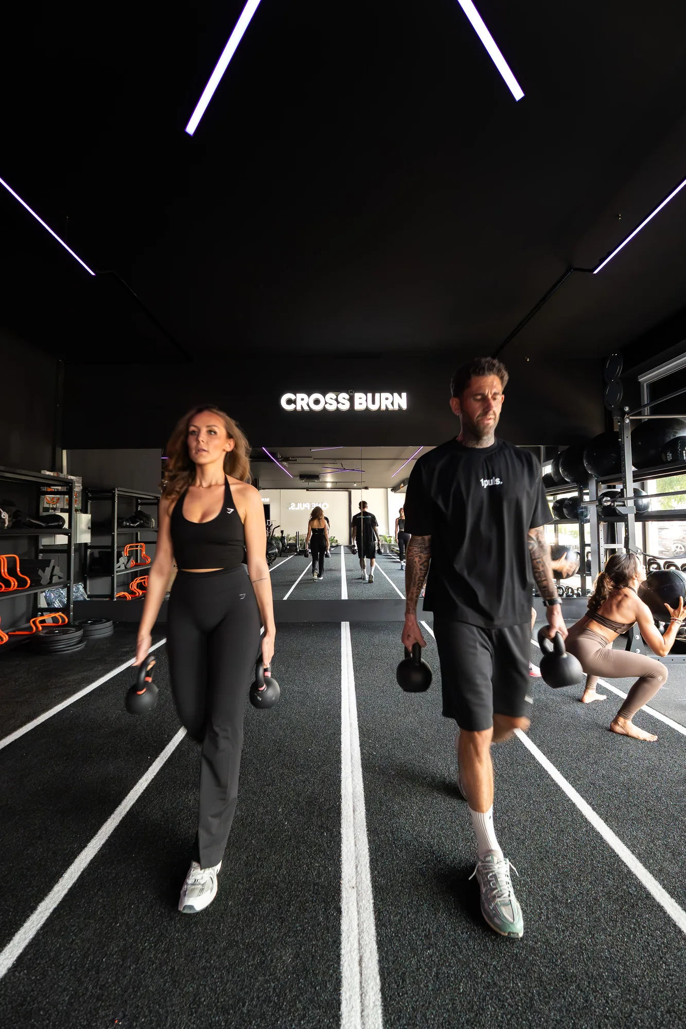 Members carrying kettlebells on the track under the HYROX sign at ONE PULS Brussels