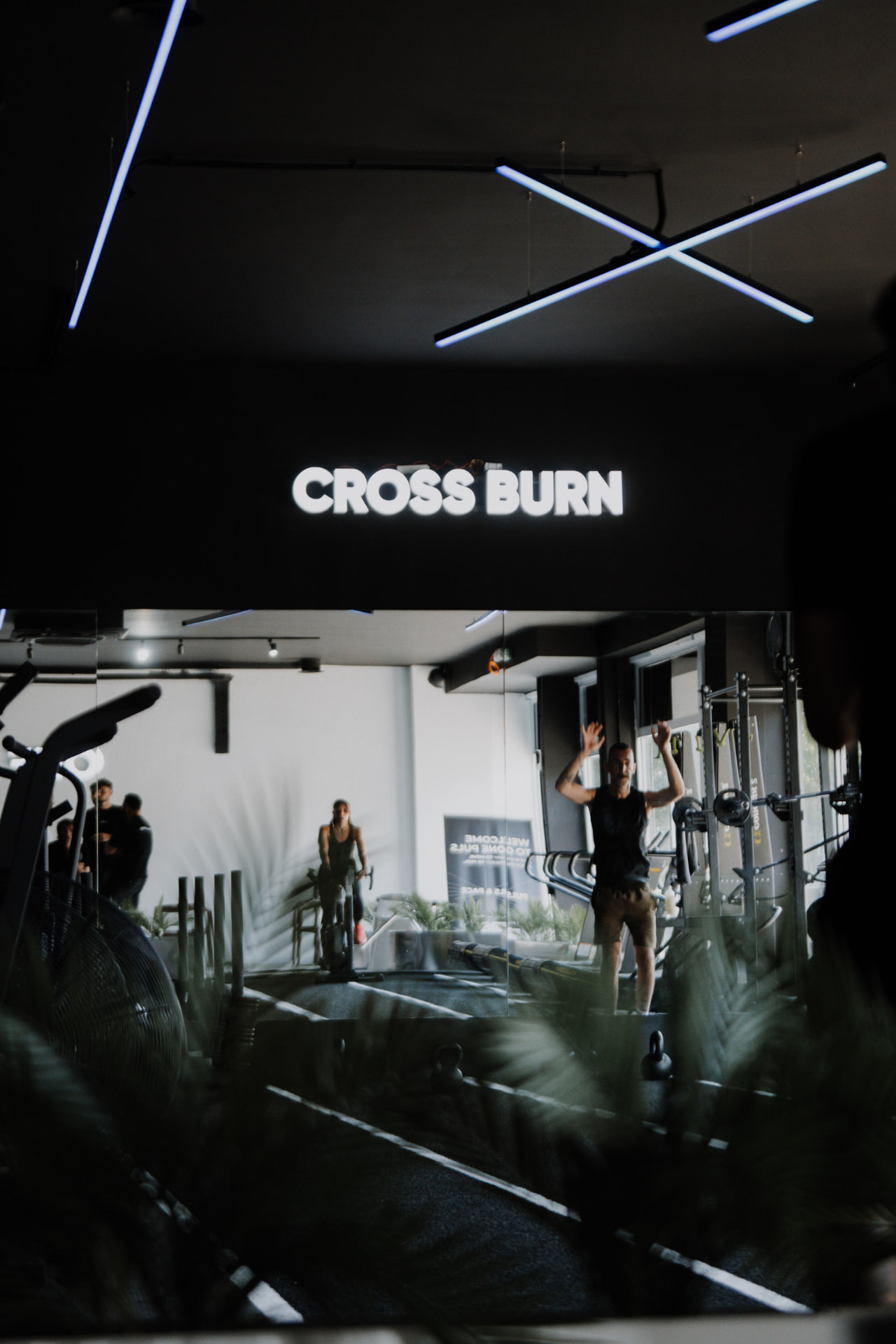 Illuminated HYROX / CROSS BURN sign above the training floor at ONE PULS Brussels