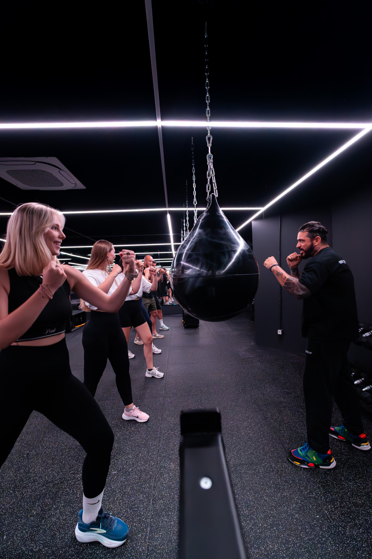 High-energy group cardio boxing workout with neon lighting at ONE PULS