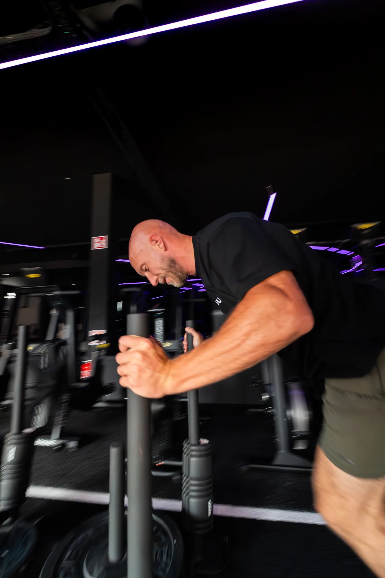 Sled push under the neon lights of the ONE PULS HYROX studio